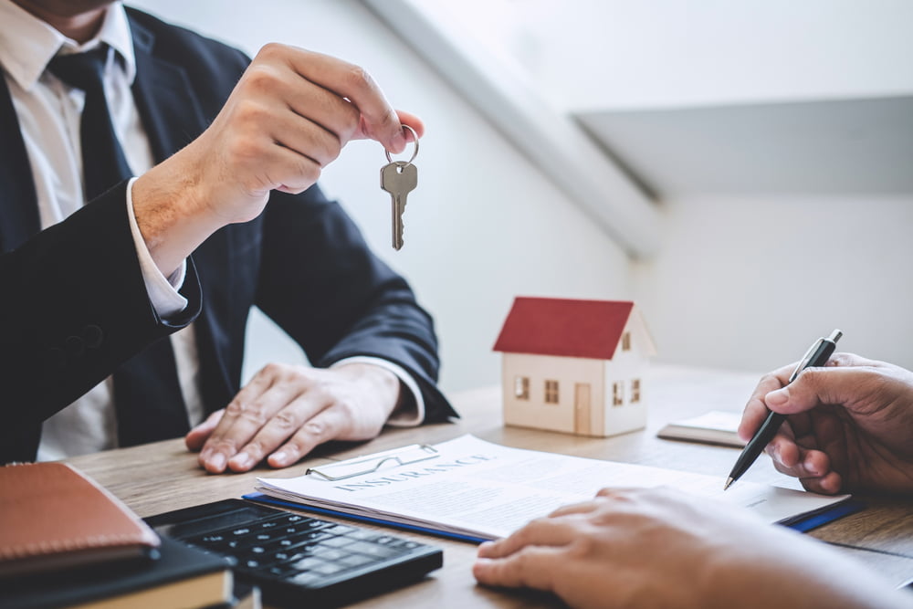 A man is handing over keys to a house as the other person secures the best home loan in Dubai.