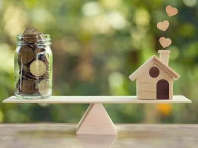house and coins on a wooden balance Balance with house and coins for mortgage refinance in Dubai